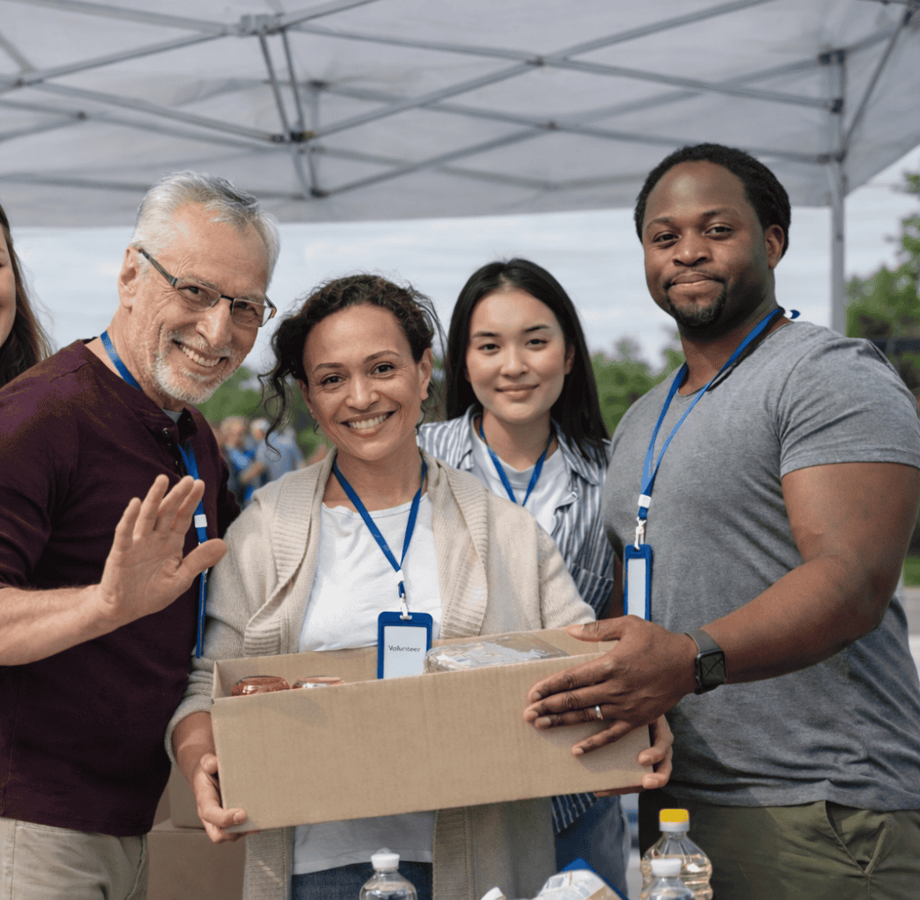 Diverse group of people at community event with a donation box.