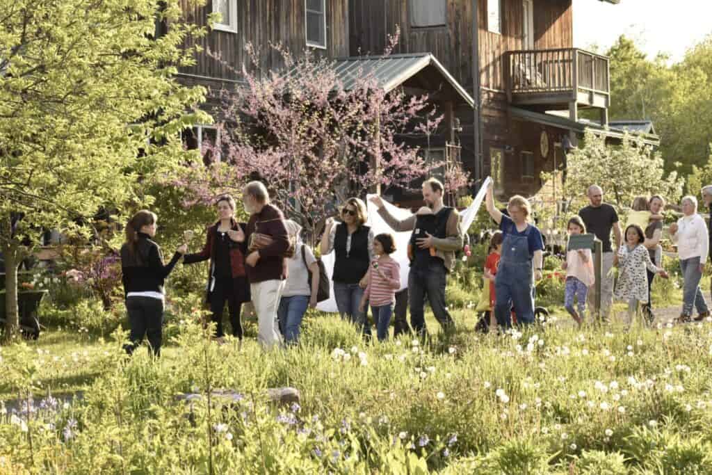 Community gathering outside a rustic wooden building with blooming trees.