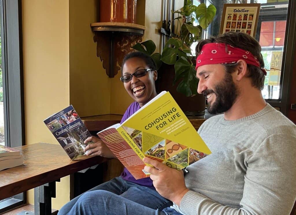 Two diverse people reading community and cohousing brochures at a cafe.