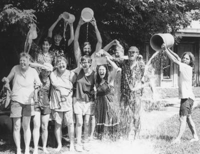 Group of people celebrating outdoors with water buckets, smiling and having fun.