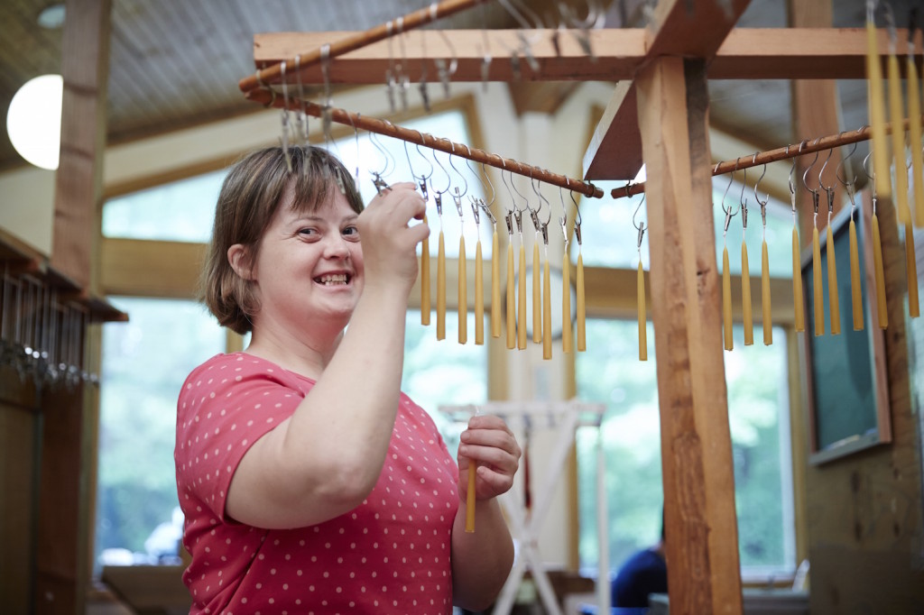 Woman smiling while hanging wind chimes in a cozy indoor space.