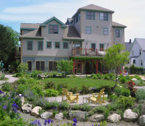 Colorful community garden with seating area in front of a large house.