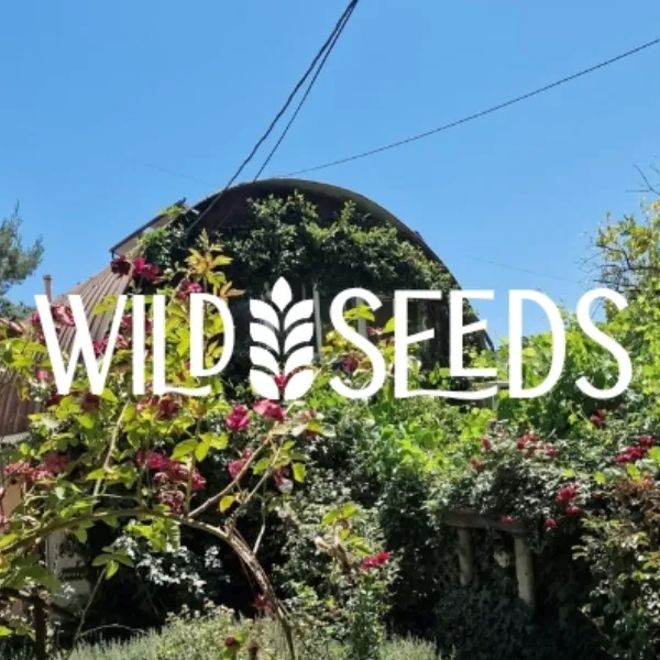 Wild Seeds Ranch sign with lush greenery and flowering plants in the background.