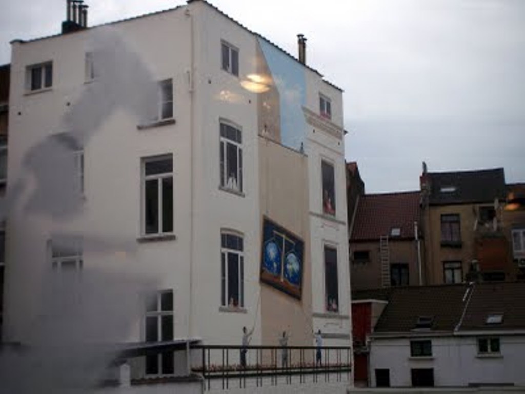 Urban building with murals and windows under cloudy sky.