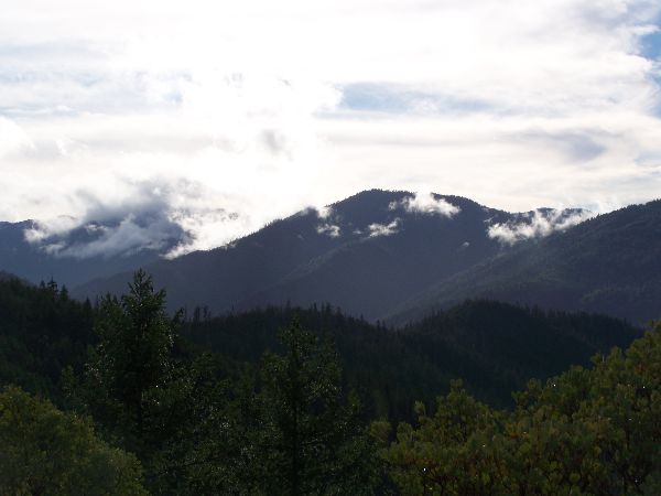 Scenic mountain landscape with forested hills and cloudy sky.