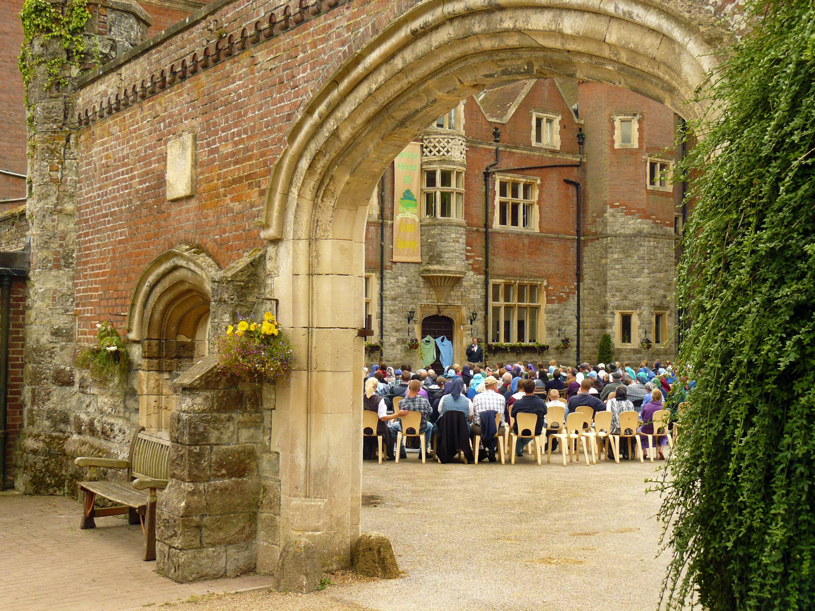 Gathering of people at an outdoor event in front of a historic brick building.