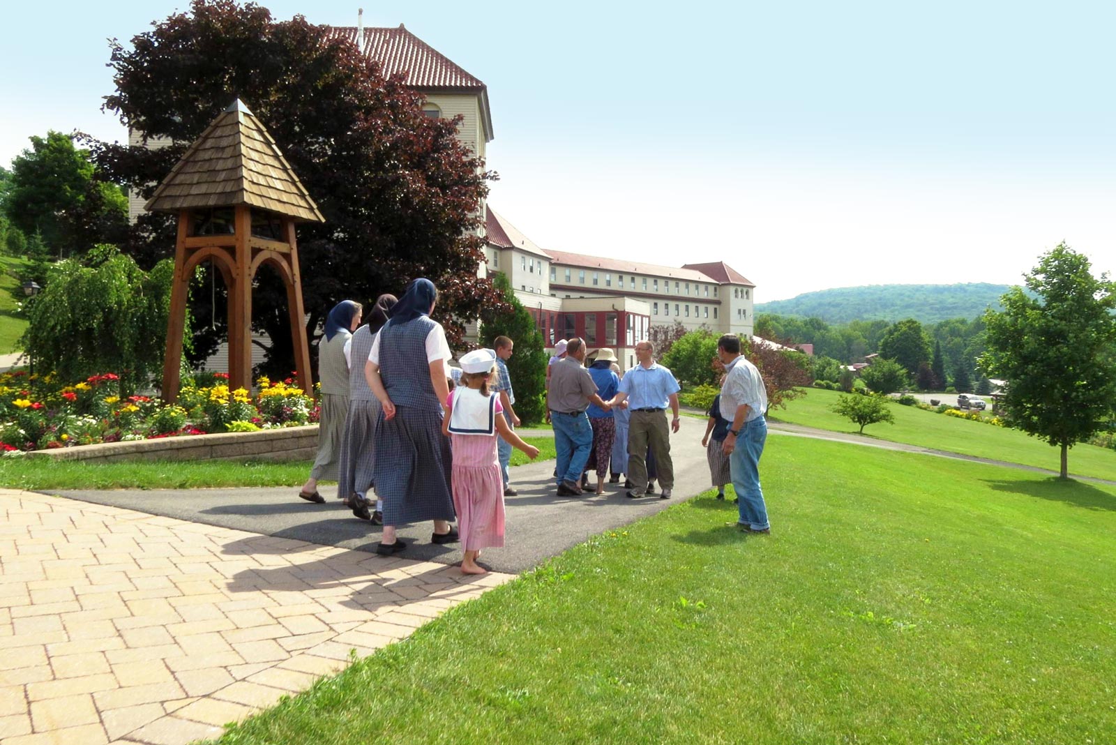 Group of people walking on a path in a lush green garden at a community center.