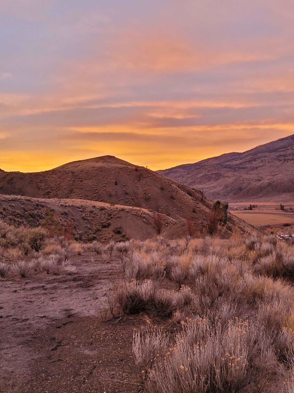 Scenic landscape of rolling hills at sunset with colorful sky.