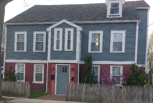 Colorful two-story house with blue siding and pink brick foundation.