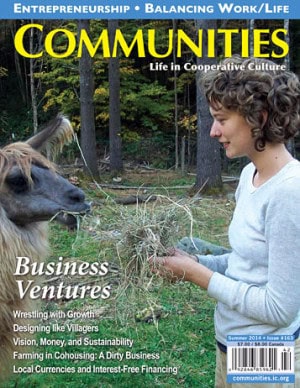 Young woman with curly hair feeding a goat in a forested community farm setting.