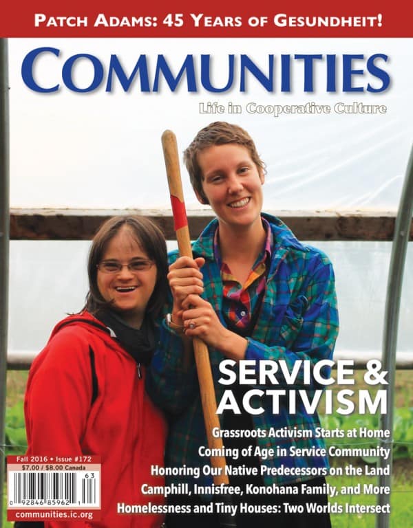 Two smiling women holding a gardening tool in a community garden.