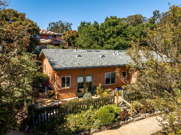 Cozy orange house surrounded by lush trees and garden in Oceano, California.