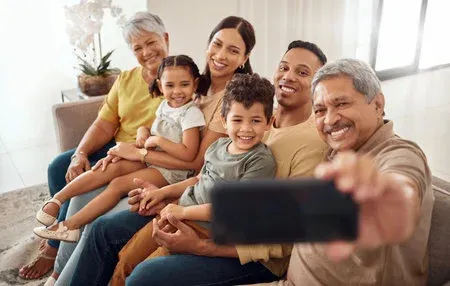 Multigenerational family taking a selfie together in a bright living room.