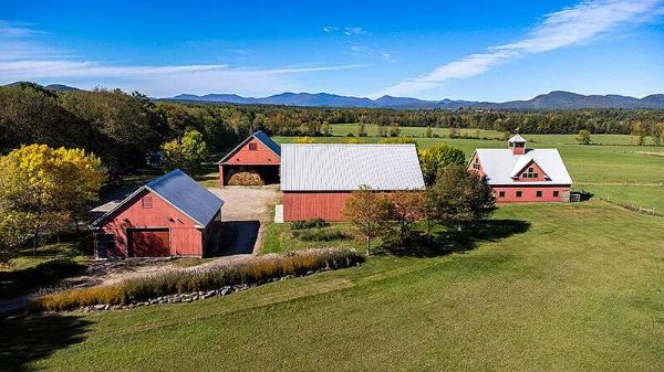 Scenic view of a farm with red barns and green fields under a blue sky.