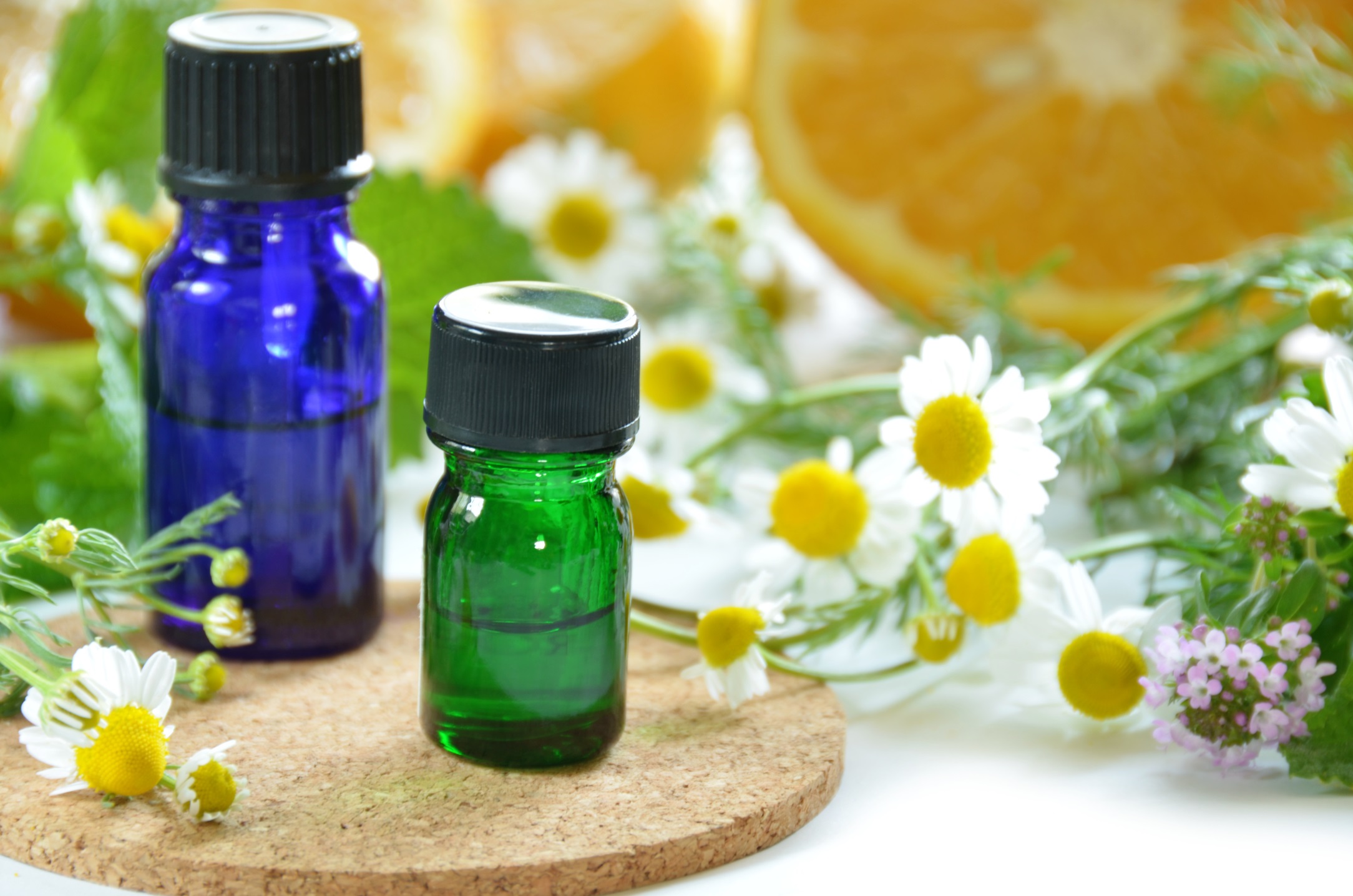 Essential oils bottles with chamomile flowers and orange slices for natural health.
