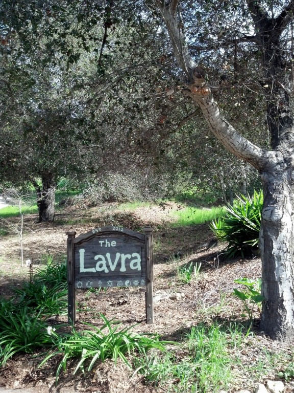 Sign for The Lavra surrounded by trees and greenery in a natural setting.