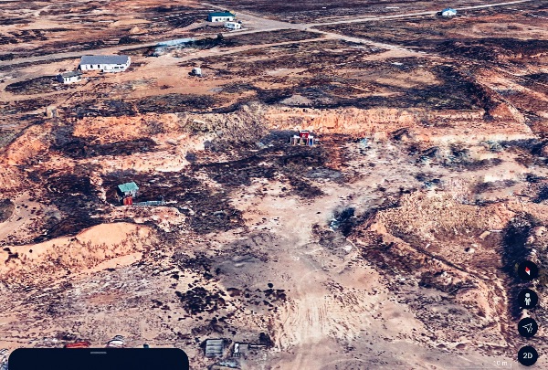 Aerial view of a community land trust with scattered small buildings and dirt roads.