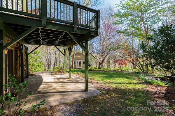 Wooden deck with stairs overlooking lush garden and trees.