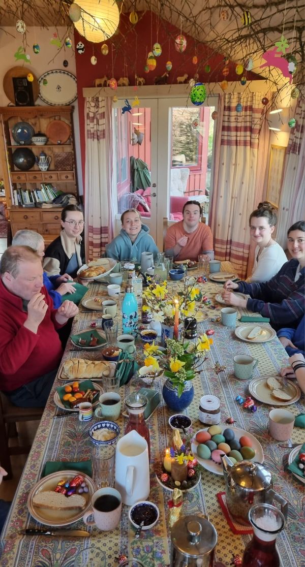 Group of people enjoying a meal at a decorated table in a cozy home setting.