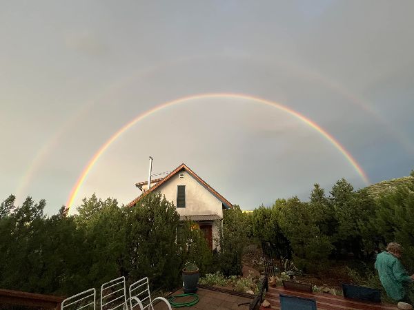 Scenic view of a house with a double rainbow in the sky.