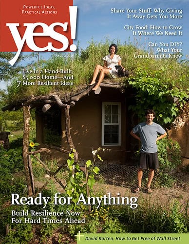 Two people in front of a cob house at Dancing Rabbit Ecovillage, green surroundings.