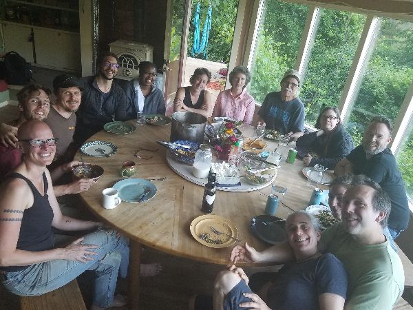 Group of people gathered around a large dining table at Cedar Moon community.