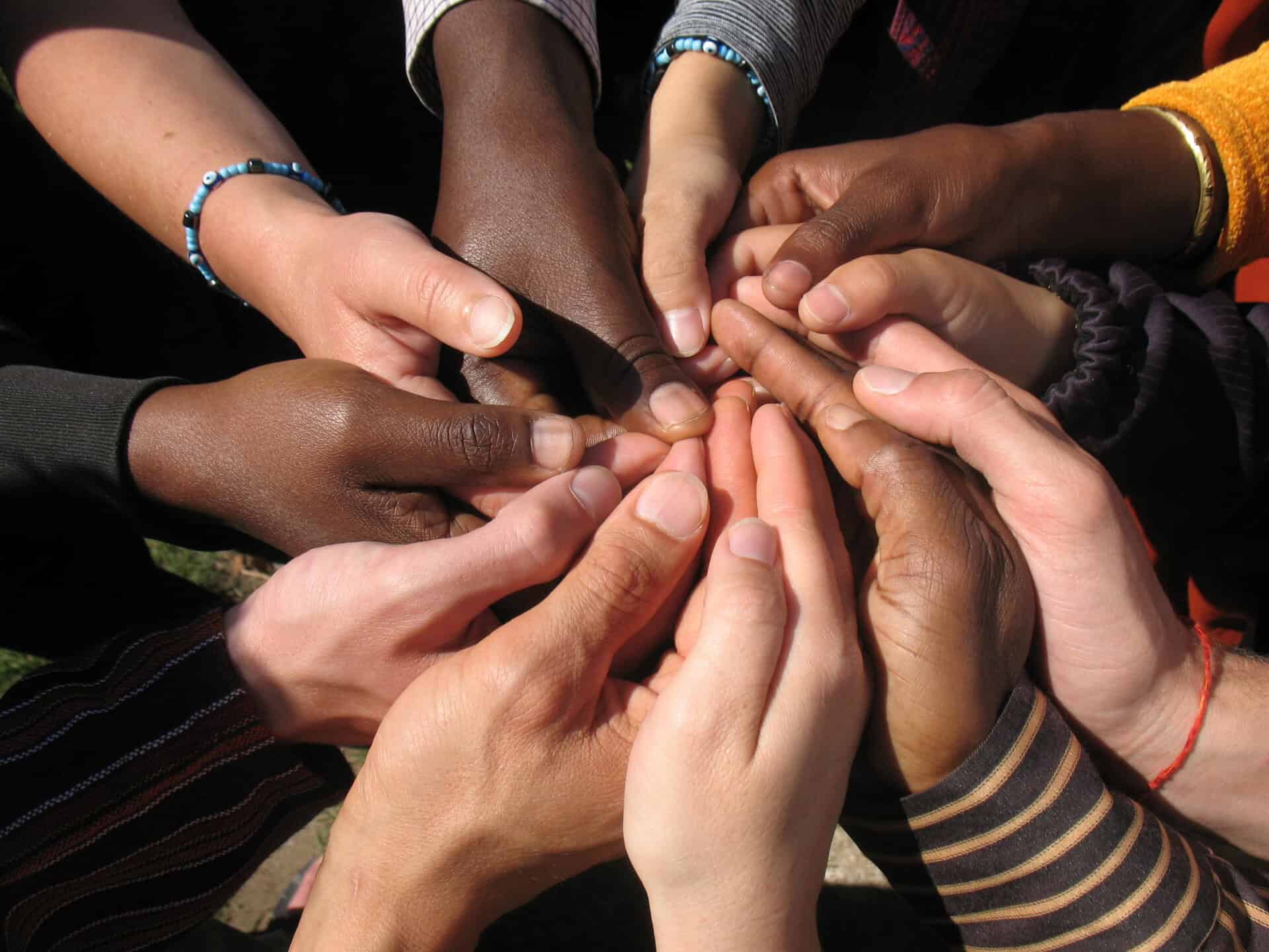 Diverse hands joined together in a circle symbolizing unity and community.