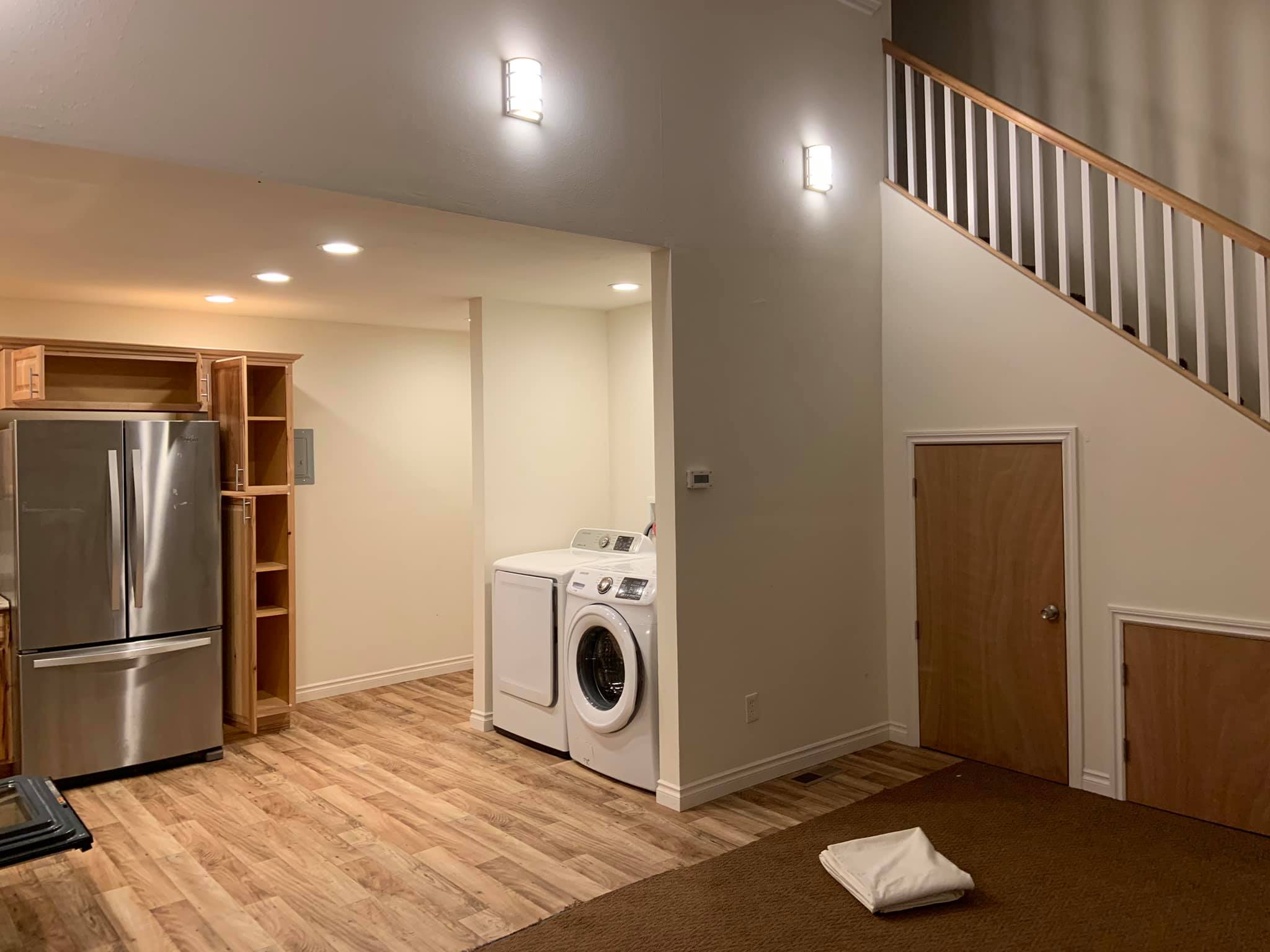 Modern laundry area with washer, dryer, and refrigerator in eco-friendly community home.