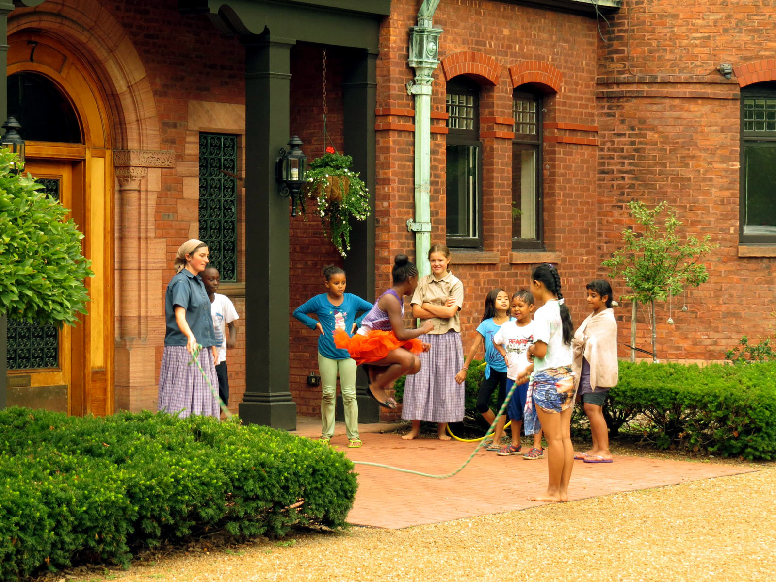 Children playing jump rope outside a historic brick building at Foundation for Intentional Community.