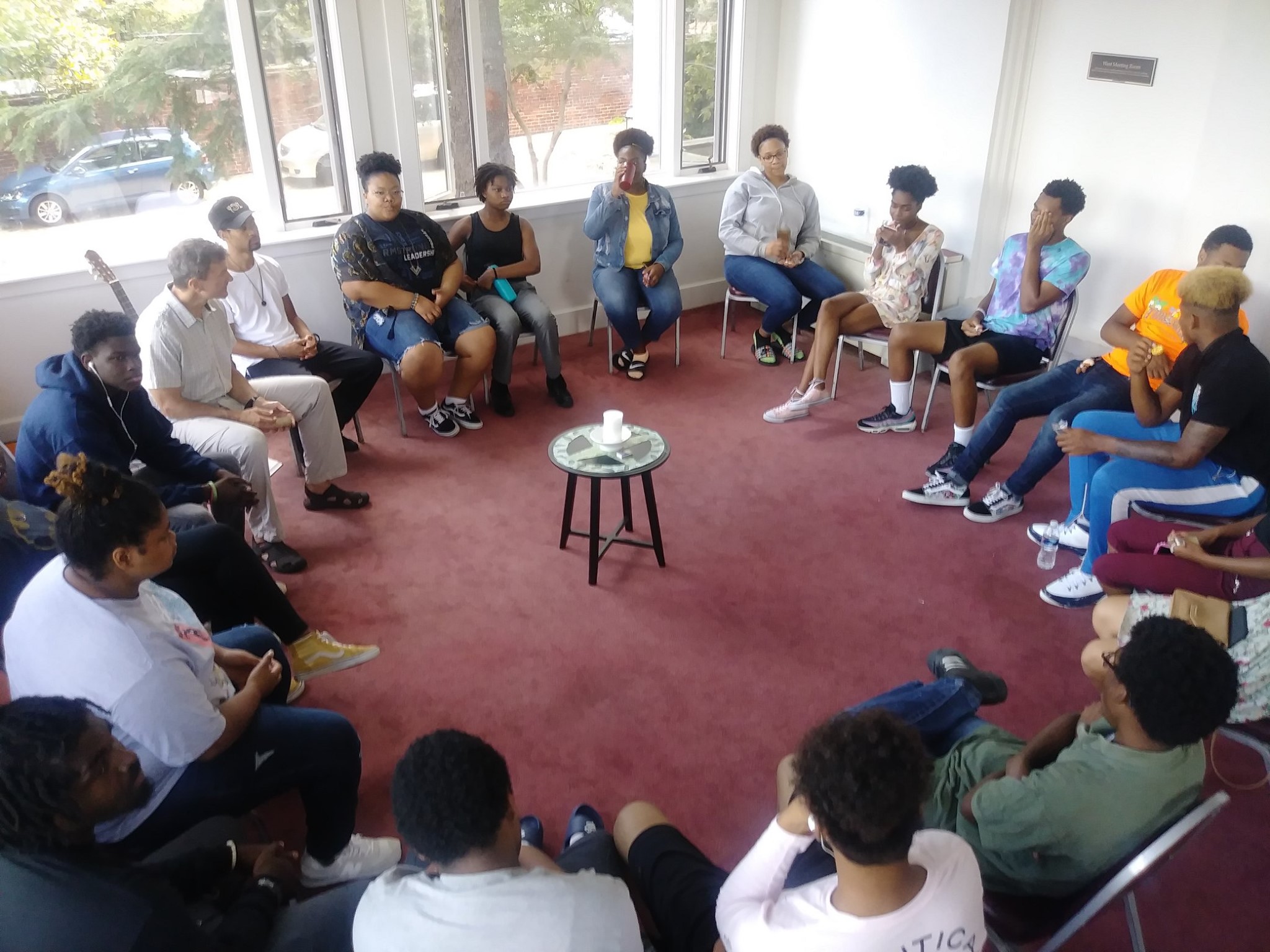 Group of diverse young people in a circle during a community meeting.
