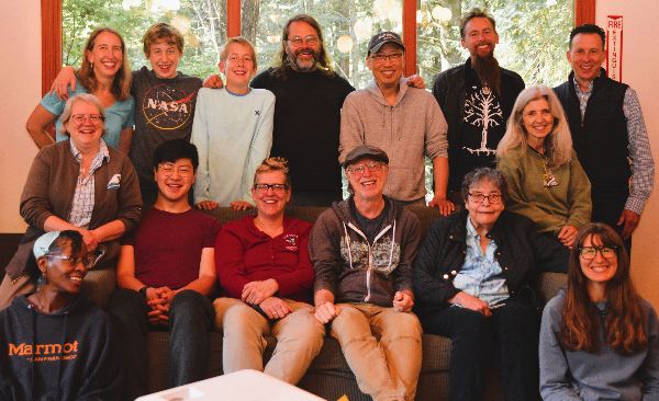 Diverse group of people smiling in a community gathering at the Foundation for Intentional Community.