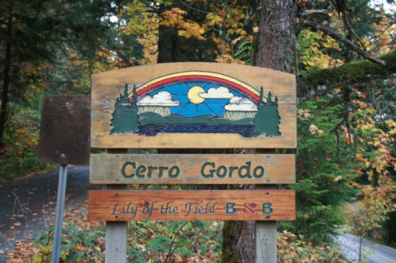 Cerro Gordo community sign with nature background and colorful artwork.