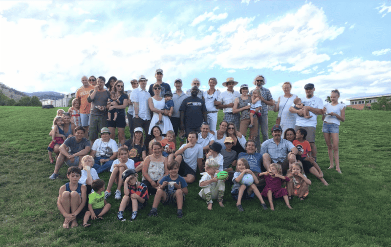 Group of diverse people enjoying outdoor gathering on a grassy hill.