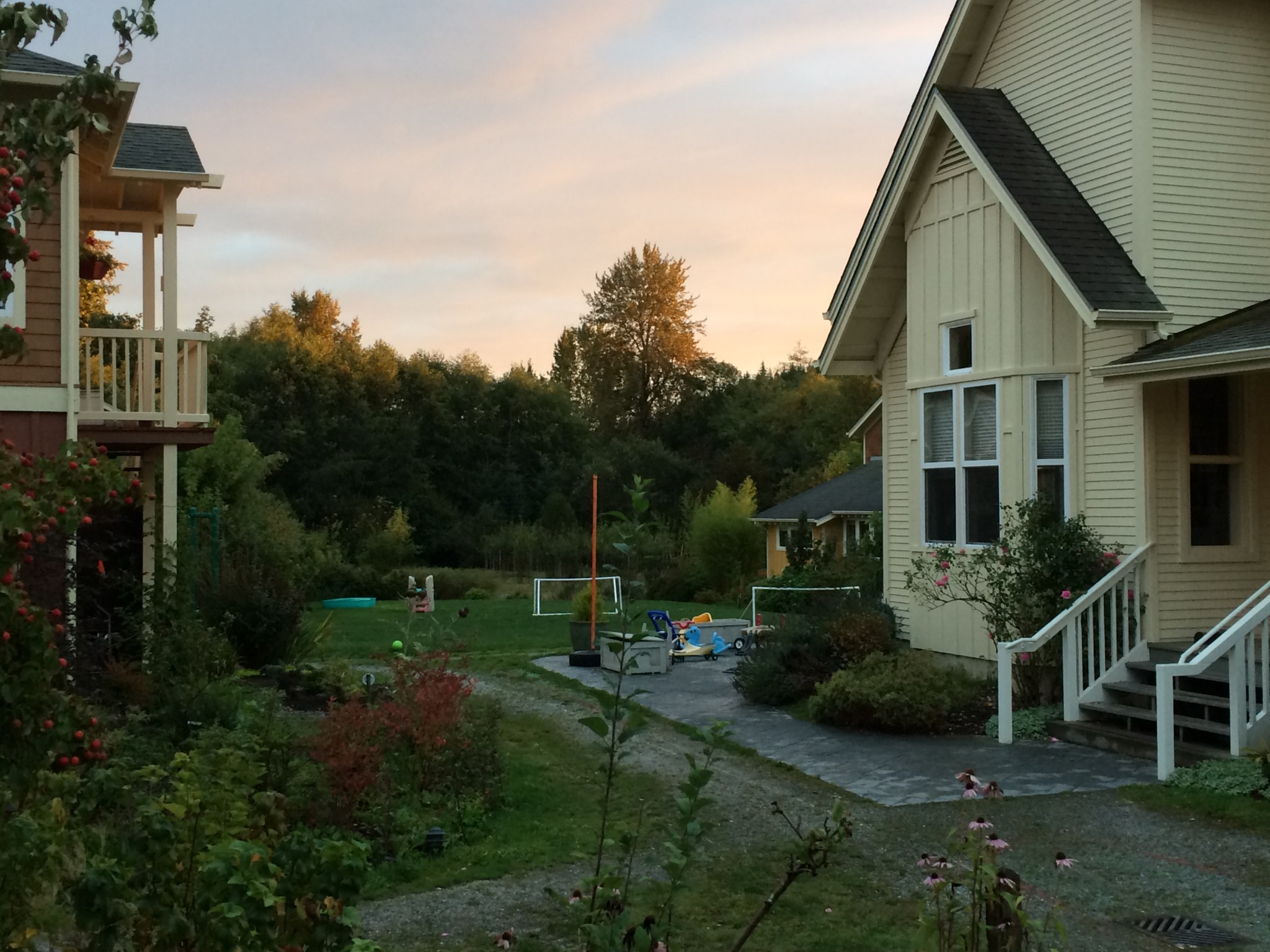 Cozy neighborhood with yellow house and lush garden at sunset.