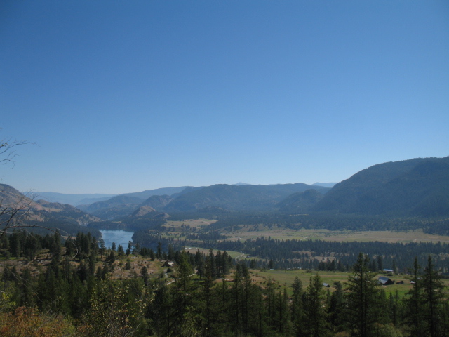 Scenic view of mountains, river, and forest in a natural landscape.