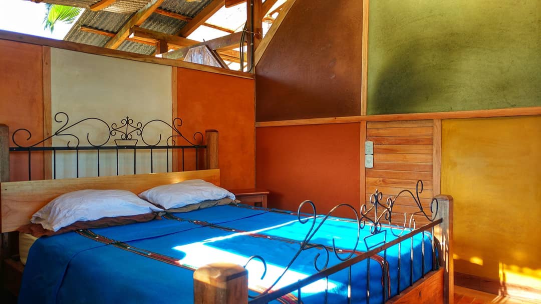 Cozy bedroom with colorful walls and a metal bed frame at Rancho Mastatal.