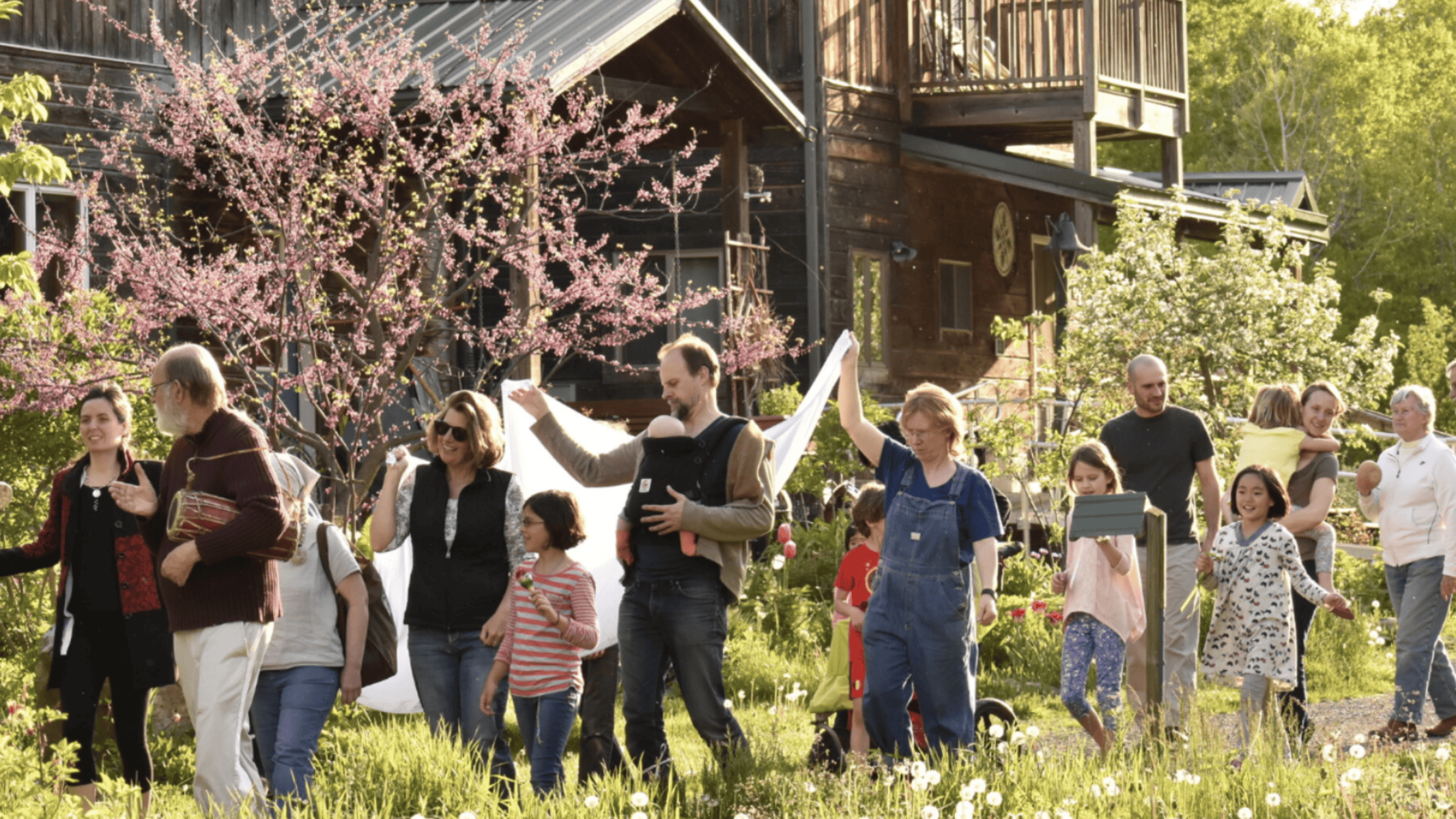 Community gathering outdoors with children and adults in a lush garden setting.