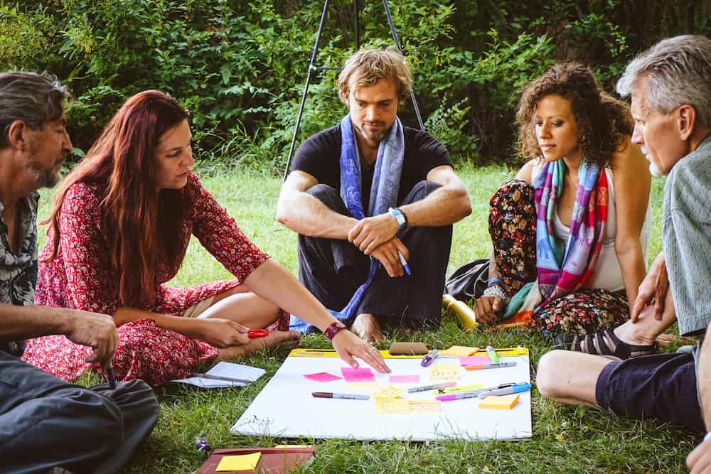 Group of diverse people collaborating outdoors with colorful sticky notes and markers.