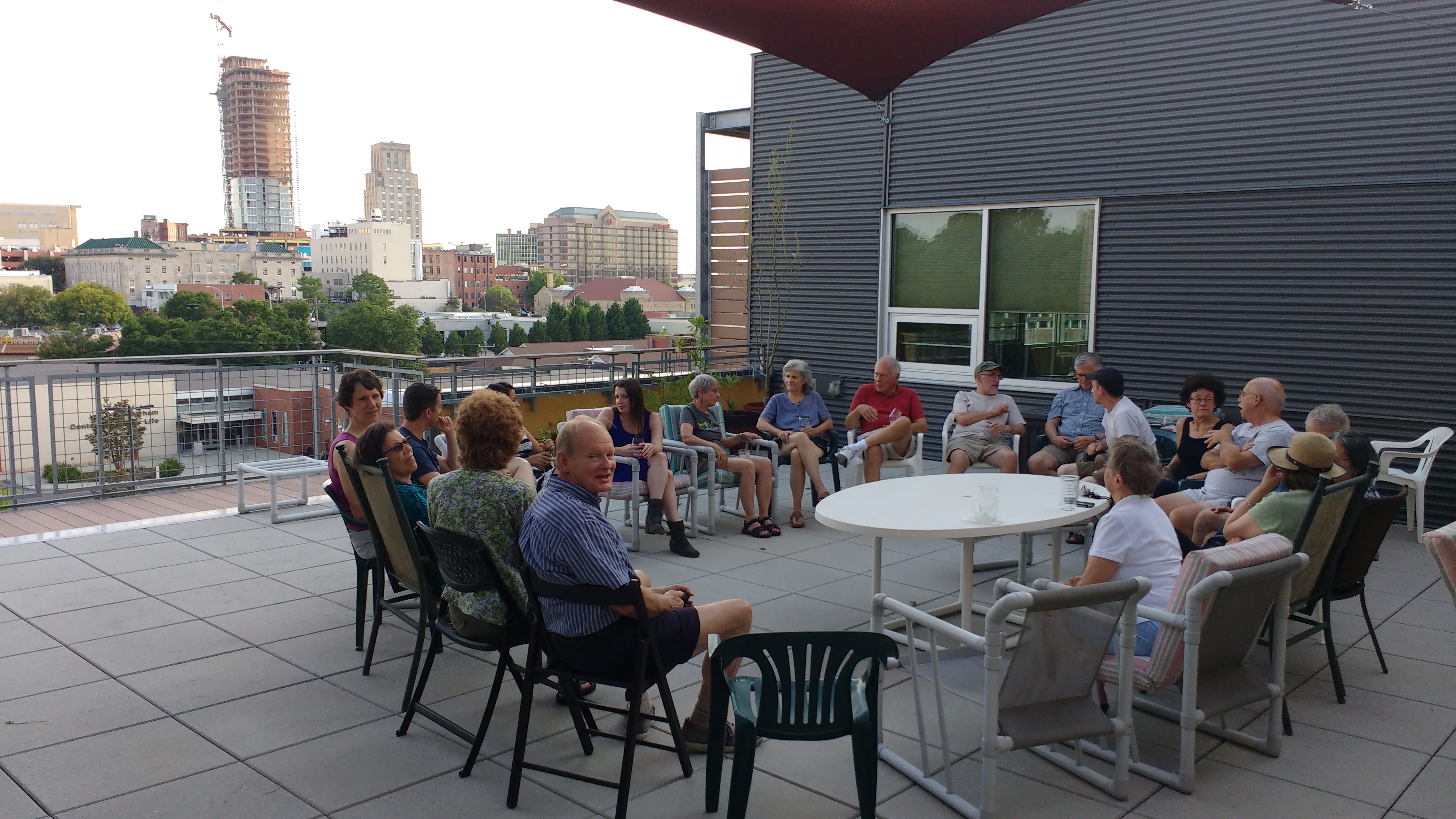 Community gathering on a rooftop terrace with city skyline in background.
