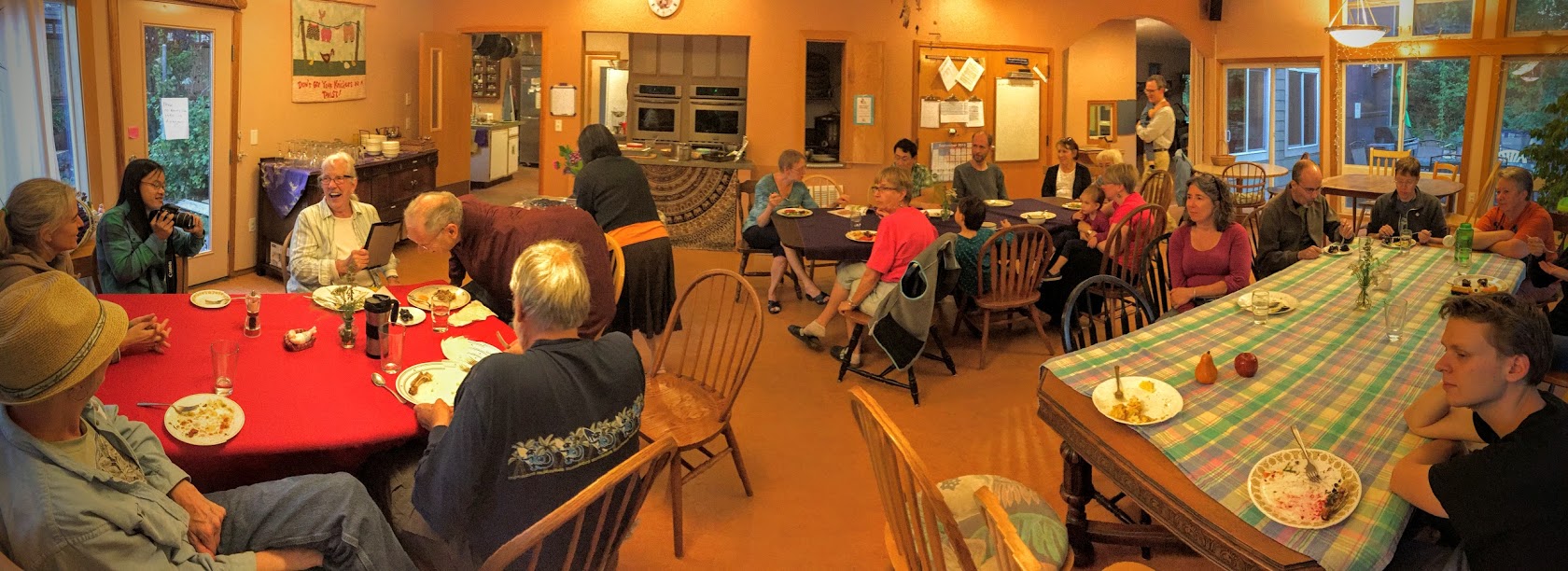 Community gathering in a warm, inviting dining room with people sharing a meal.