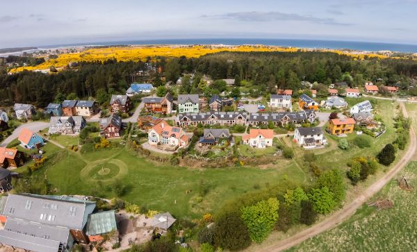 Aerial view of Findhorn Foundation Ecovillage with colorful houses and lush greenery.