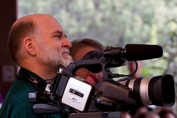 Man operating professional video camera at community event.