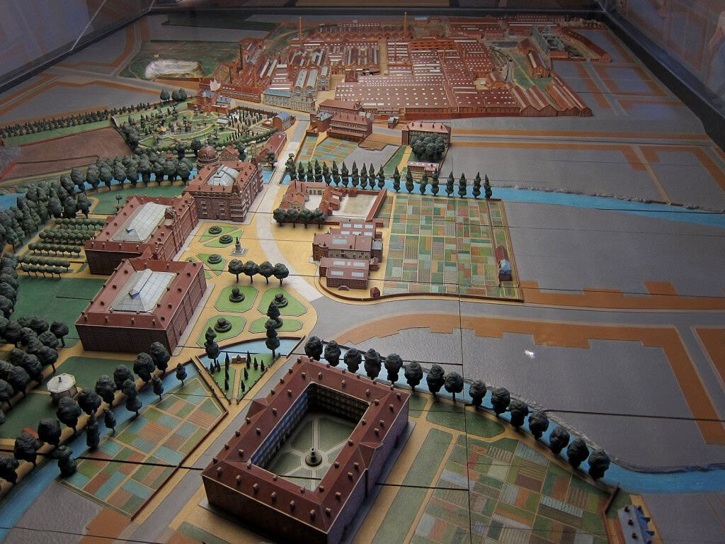 Detailed model of a historic community with buildings, gardens, and water features.