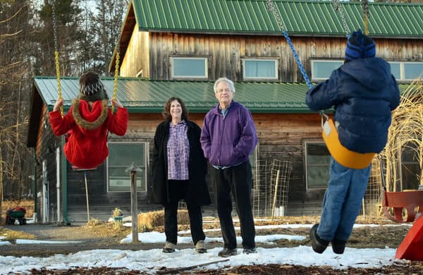 Family enjoying outdoor time at a sustainable community with a wooden house.