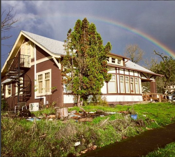 Colorful rainbow over a large house with trees in Eugene, OR.
