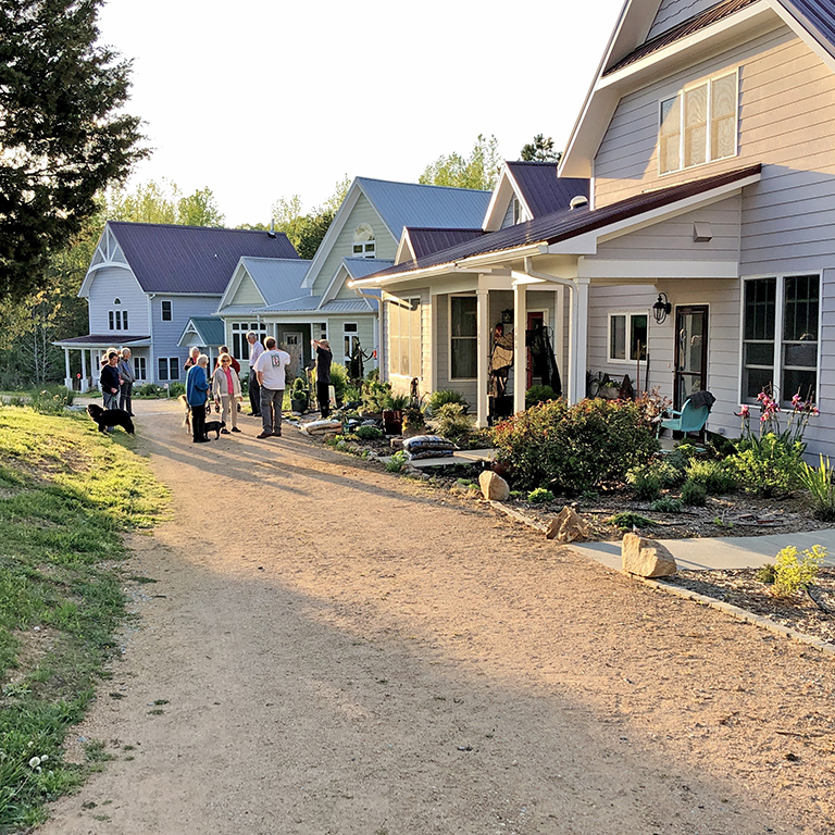 Community gathering outside Elderberry Cohousing Village homes at sunset.