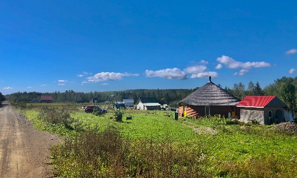 Scenic rural landscape with traditional roundhouse and surrounding greenery.