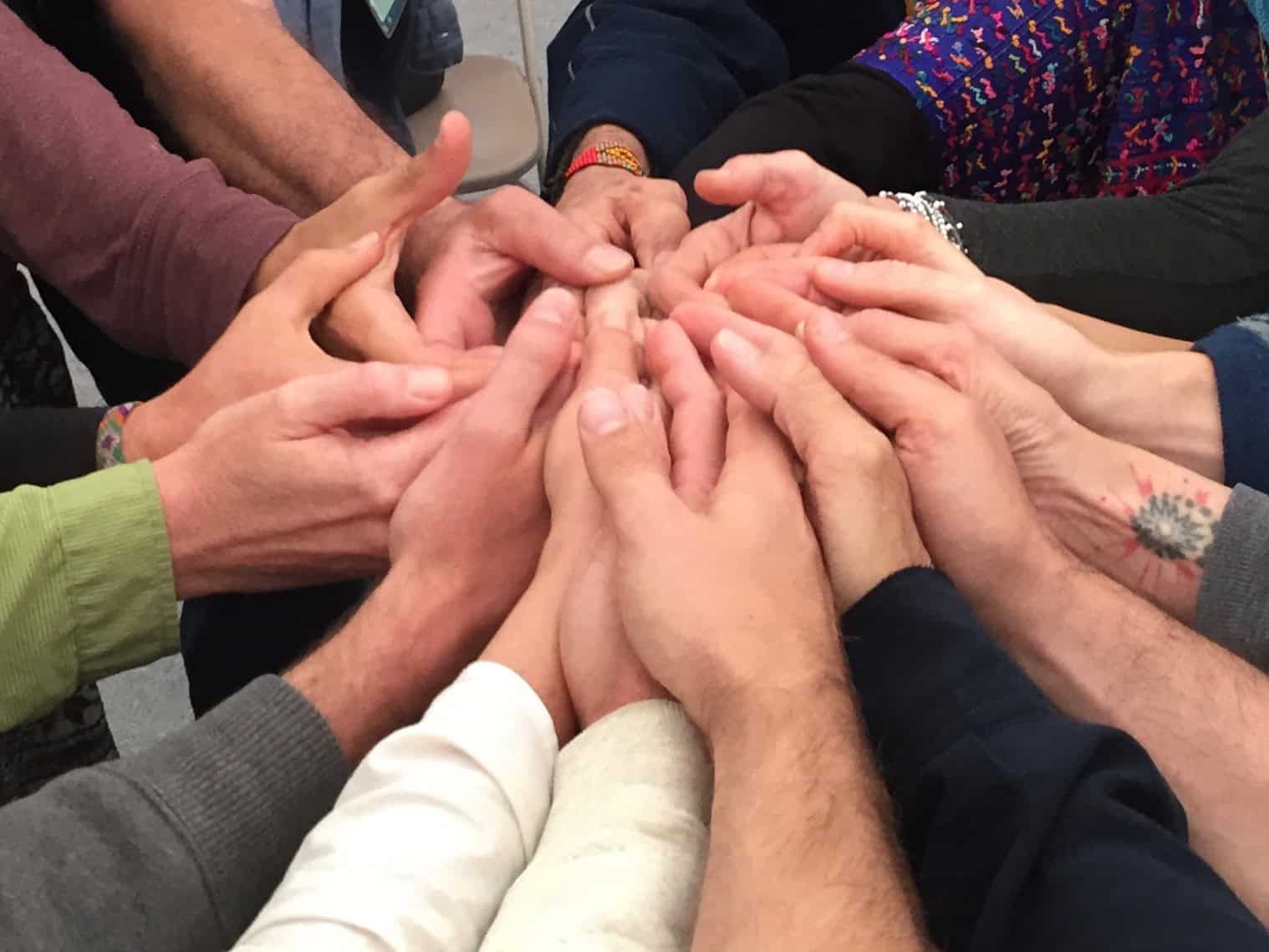 Group of diverse people placing hands together in unity and teamwork.