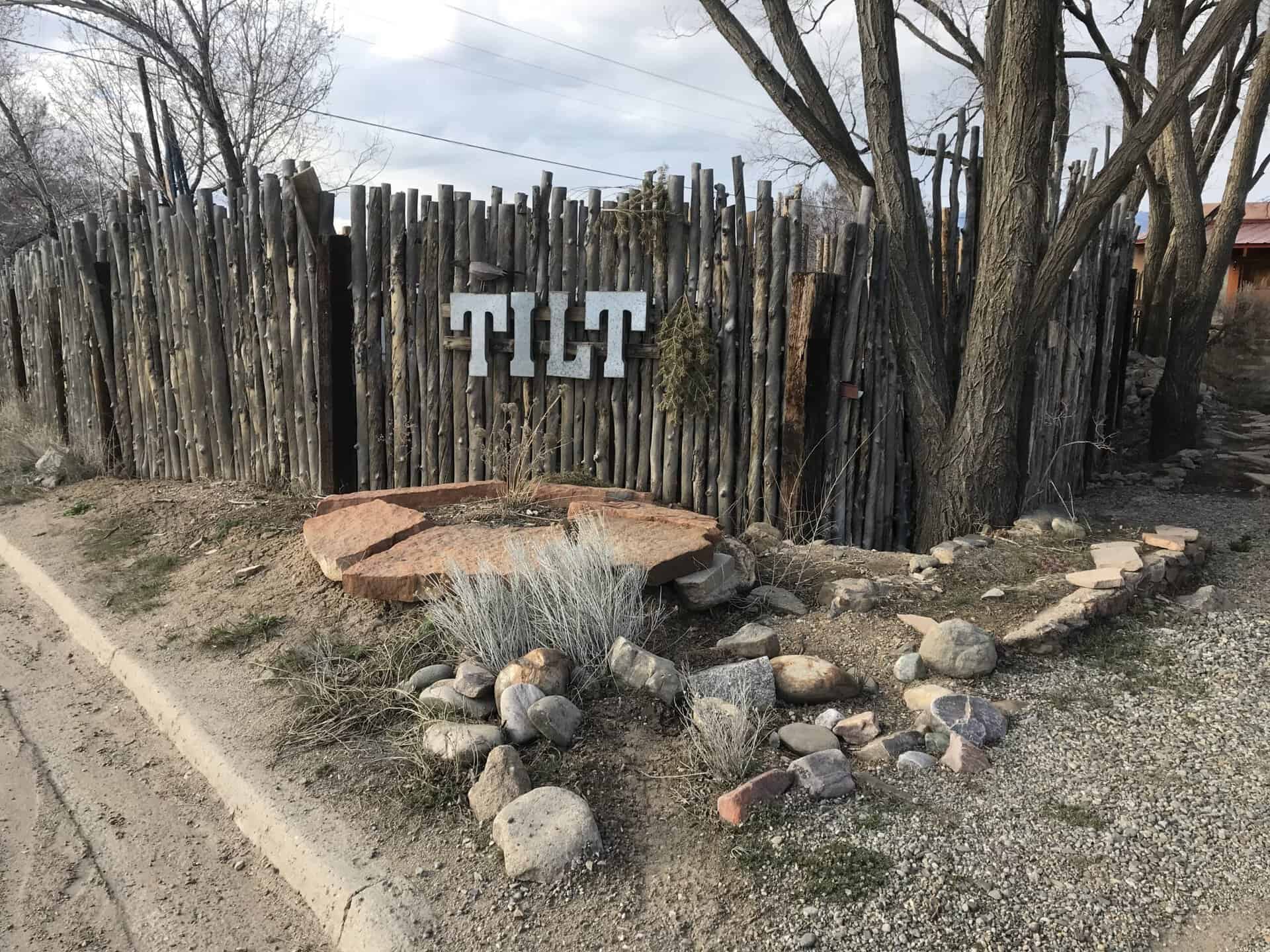 Community entrance sign with wooden fence and natural landscaping in Taos, New Mexico.