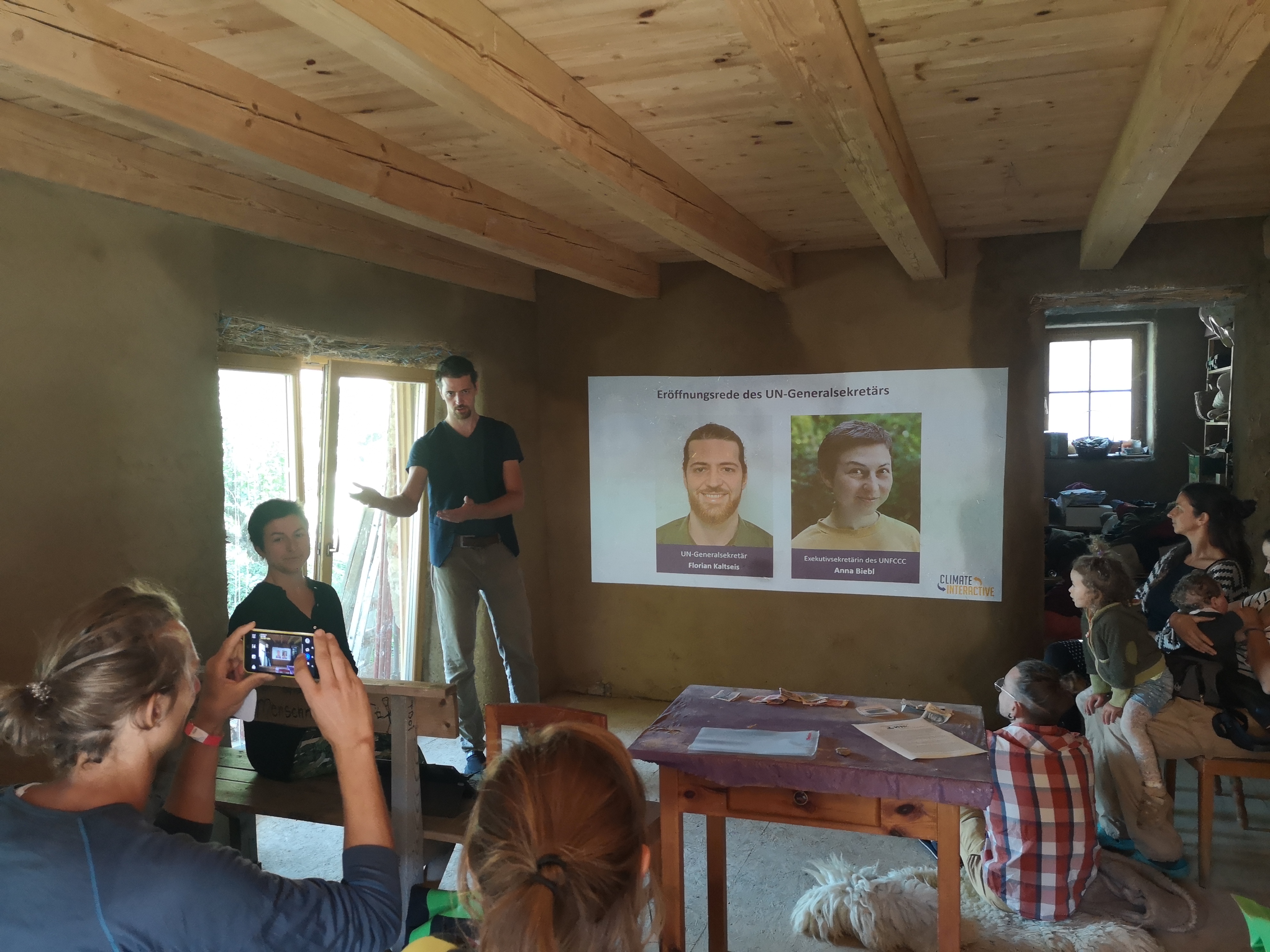 People attending a presentation in a rustic room with a projector screen.
